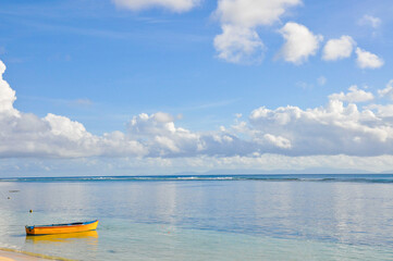 Tropical seascape with yellow small local boat horizon over the water and blue sky