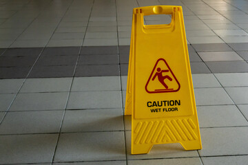 Wet cleaning of the room on the wet tile floor is a yellow stand with the inscription "careful slippery floor". Copy space.
