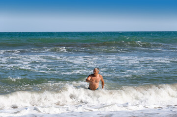 A middle-aged man comes out of the sea. Black Sea, summer, Crimea.