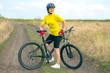 Beautiful and happy girl cyclist with a bike on nature. Healthy lifestyle and sports. Leisure and hobbies