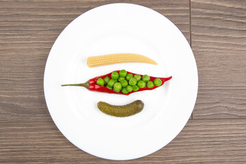 salad of pickled and pickled corn, peas, cucumber and red pepper on a white plate.  food and vegetables. diet and weight loss
