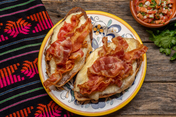 Mexican molletes with bacon and pico de gallo sauce on wooden background