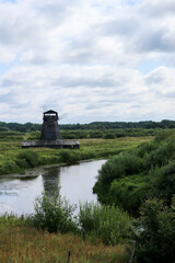 old abandoned wooden windmill in the field by the river