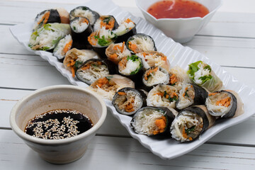 Vegan Vietnamese spring rolls on white platter, chili and soy sauce
