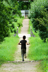 young boy running on the beautiful park alley