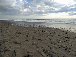 Sea in Marina di Bibbona at sunset, evening sky with clouds, Italy. Mediterranean Sea, beautiful sandy beach, waves.