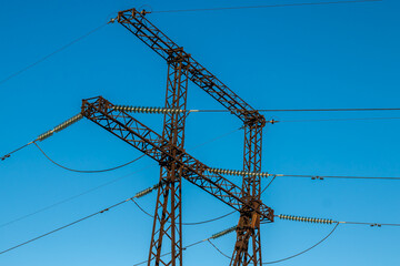 Metal support tower of power line against blue sky background. Close-up.
