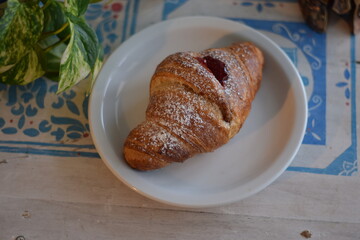 Un corazon de frambuesa dulce dentro de un croissant .