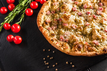 Traditional Italian focaccia among tomato and spices on a dark background, studio light. Traditional food concept