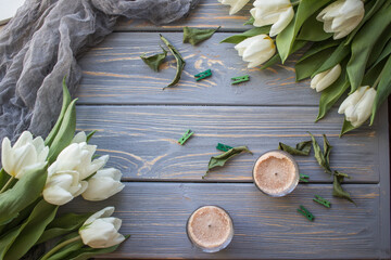 White tulips and candles on a blue wooden background. Top view with copy space.