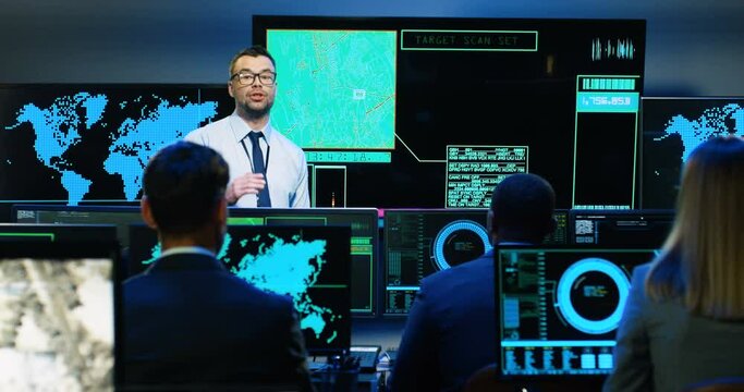 Caucasian man professional army analytic talking at maps and screens with geolocations, explaining cybersecurity to mixed-races people. Multiethnic military workers listening to male security speaker.