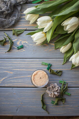 White tulips and candles on a blue wooden background. Top view with copy space.