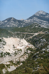 Top view of a mountain serpentine road on a mountain wasteland with green trees and mountain views.