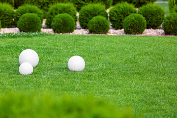 backyard 3 lights garden with electric ground lanterns with sphere diffuser lamps in lawn in outdoors park with copy space landscaping cypress bushes in stone mulching, nobody.