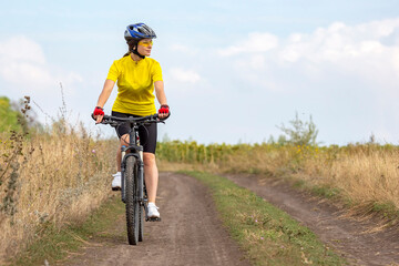beautiful and happy girl cyclist rides a bicycle on the road in nature. Healthy lifestyle and sports. Leisure and hobbies