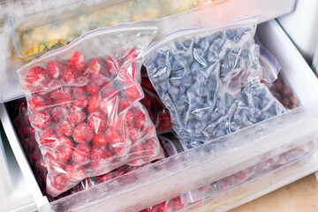 Berries on the freezer shelves. Frozen food in the refrigerator.
