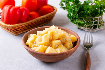 Stewed potatoes with meat in a ceramic bowl on a light background