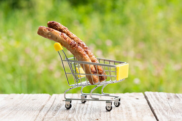 Meat sausages are in a small cart for frying on the fire.
