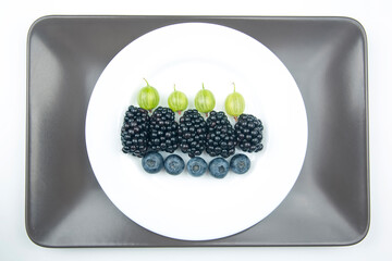 berries blueberries, gooseberries and blackberries on a white plate. useful vitamin healthy food fruit. healthy vegetable breakfast