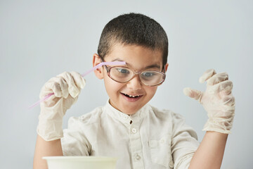 Funny kid making experiments at the workshop and exploring the world of chemistry against the white background