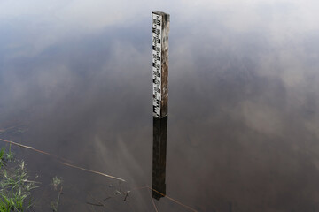 A wooden pillar with a steel flood level or water depth scale installed in a river or a lake. The...