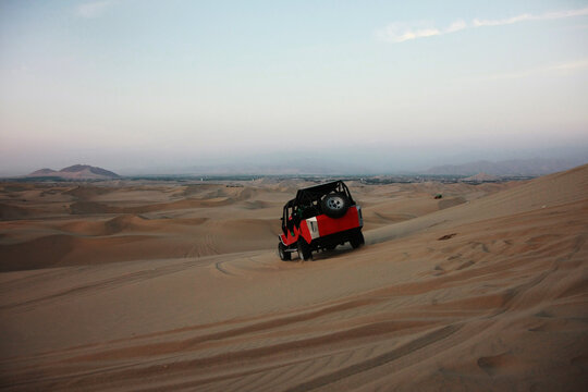 A buggie that is riding over the sand dunes in the desert nearby Ica in Peru with tourists