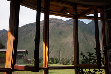 Large glass windows that are opened and have a beautiful view on a large with grass covered mountain