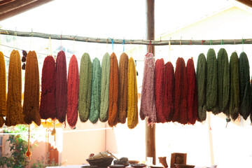 Wool dyed in different colors with natural paint that is hung up to dry on a wooden stick