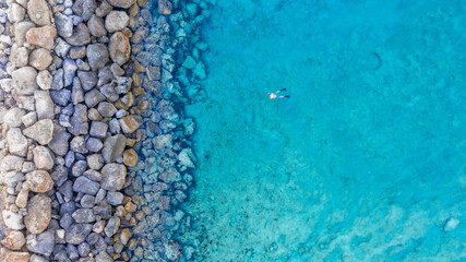 An aerial view of the beautiful Mediterranean Sea and a swimmer, where you can see   the cracked...