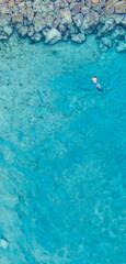 An aerial view of the beautiful Mediterranean Sea and a swimmer, where you can see   the cracked rocky textured underwater corals and the clean turquoise water of Protaras, Cyprus, 