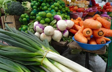 The many vegetables at a market in Ecuador, South America such as carrot, lemons, brocceli, onions, leech, tomatoes and more