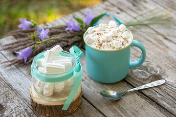 Morning coffee with foam and marshmallows with flowers in nature.