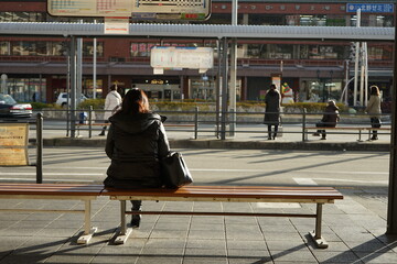 person walking on the street \Wait\She wait\alone \Who are you waiting for?\Woman siting in bus stop