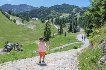 Naklejka premium Boy walking with view to the mountain Vogel Ski Resort in Slovenia in summer