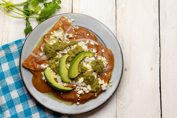 Mexican enfrijoladas with green sauce on white background