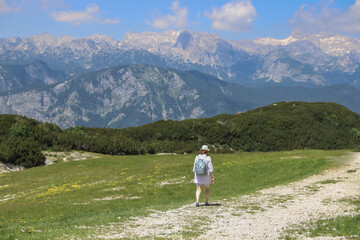 Fototapeta na wymiar Woman walking with view to the mountain Triglav in Vogel Ski Resort, Slovenia in summer