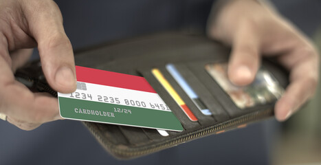 Pulling plastic bank card with flag of Hungary out of the wallet, fictional card number