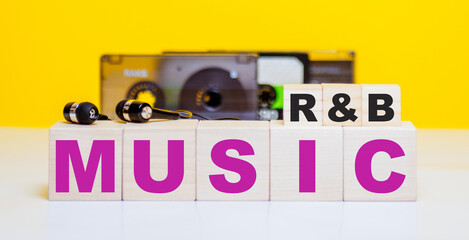 Wooden cubes with the inscription R&B MUSIC on the background of audio tapes and headphones....