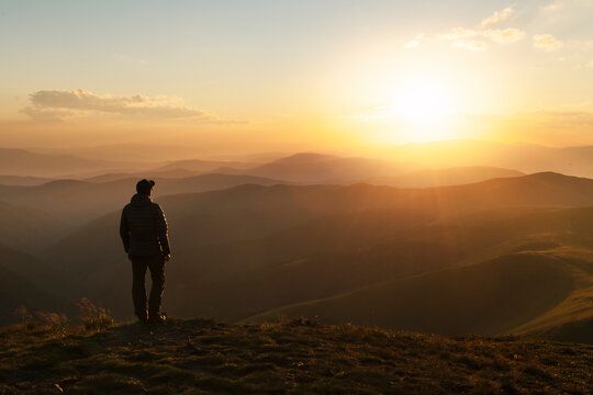 Alone tourist on the edge of the cliff against the backdrop of an incredible sunset mountains landscape