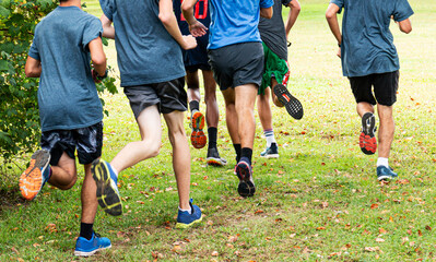 Rear view of boys running on grass turning left around bush