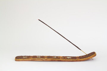 An incense stick on a wooden holder on a white background