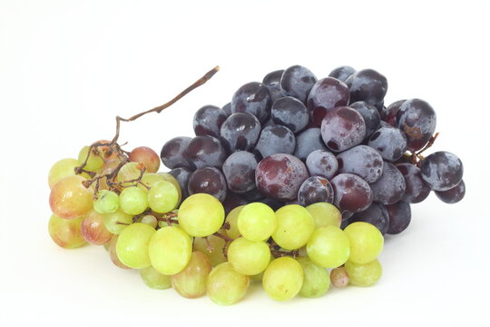 Black and green delicious grapes on a white plate close up
