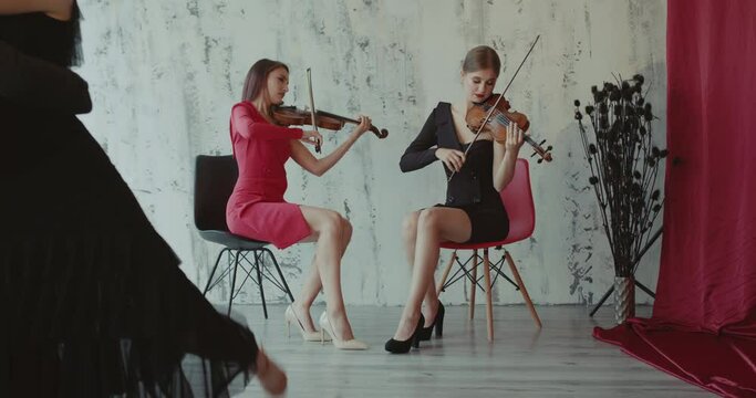 Beautiful view of dancers couple perform tango while girls play the violin