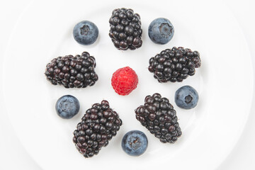 blueberries, raspberries and blackberries on a white plate