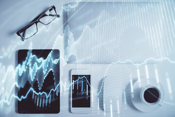 Double exposure of forex chart hologram over desktop with phone. Top view. Mobile trade platform concept.