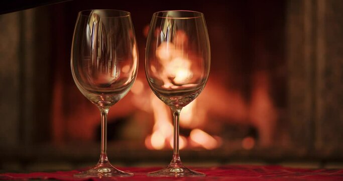 Pouring glasses of red wine by fireplace. Cozy romantic evening. Slow motion. 4k graded from RAW. Staying at home happy moments.