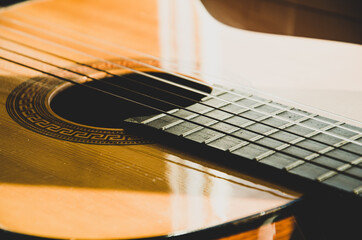 Fototapeta premium Close-up of guitar strings in sunlight. Guitar fretboard part, acoustic six-string wooden guitar, stringed musical instrument.
