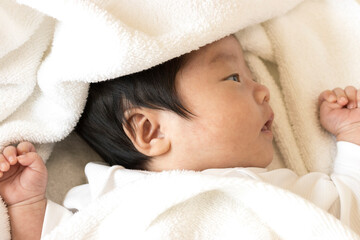 タオルに包まれている生後一ヶ月の赤ちゃん