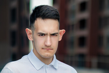Portrait of handsome frustrated serious young man, funny cool upset guy with big ears looking at...