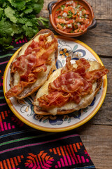 Mexican molletes with bacon and pico de gallo sauce on wooden background